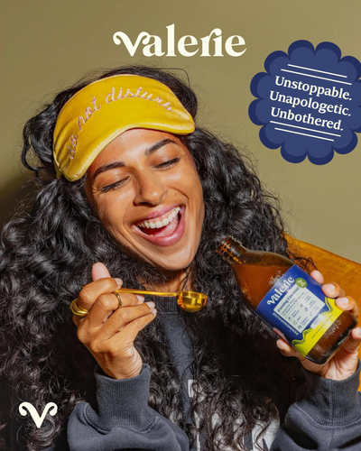 Person wearing a yellow sleep mask and holding a bottle labeled 'Valerie' with a quote about being unstoppable, unapologetic, and unbothered.